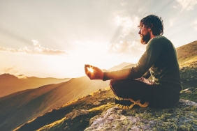 Man meditating yoga lotus pose at sunset mountains Travel Lifestyle relaxation emotional concept summer vacations outdoor harmony with nature calm scene