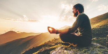 Man meditating yoga lotus pose at sunset mountains Travel Lifestyle relaxation emotional concept summer vacations outdoor harmony with nature calm scene
