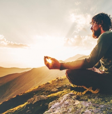 Man meditating yoga lotus pose at sunset mountains Travel Lifestyle relaxation emotional concept summer vacations outdoor harmony with nature calm scene